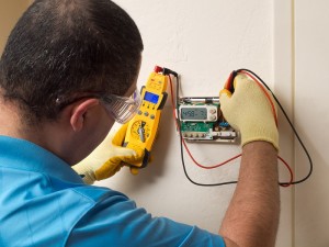 Technician fixing the wall mounted control panel for a HVAC system.