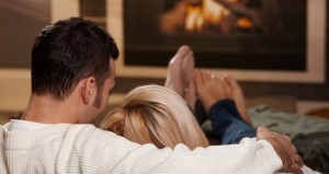 Couple laying down on couch in front of fire enjoying total comfort.